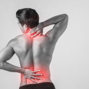 Picture of a young man's back with his hands on his neck and low back with red in those areas indicating pain