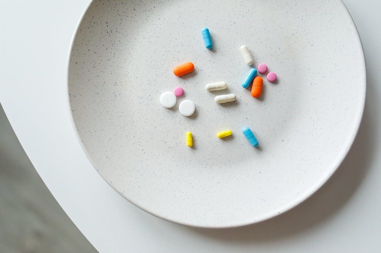 Pills and capsules of various colors on a plate