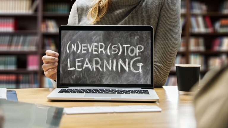 Woman behind a laptop with the screen saying Never stop Learning