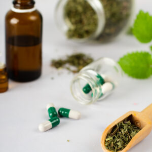 Medical capsules surrounded by herbs, dried, fresh, and liquid extract
